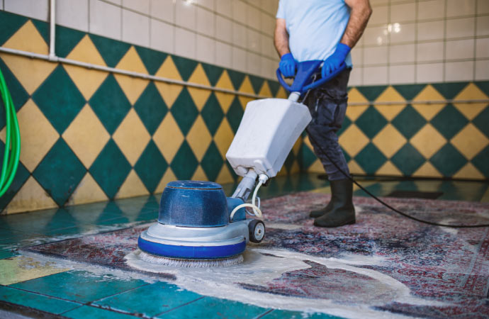 A worker diligently repairing and cleaning a rug